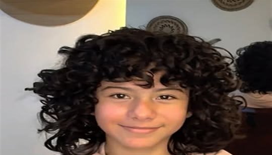Joven con rizos y flequillo rizado, sonriendo