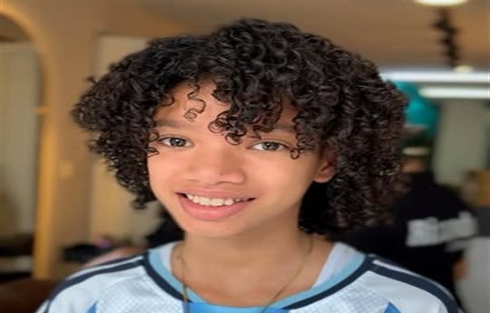 Niño con rizos definidos y camiseta de fútbol