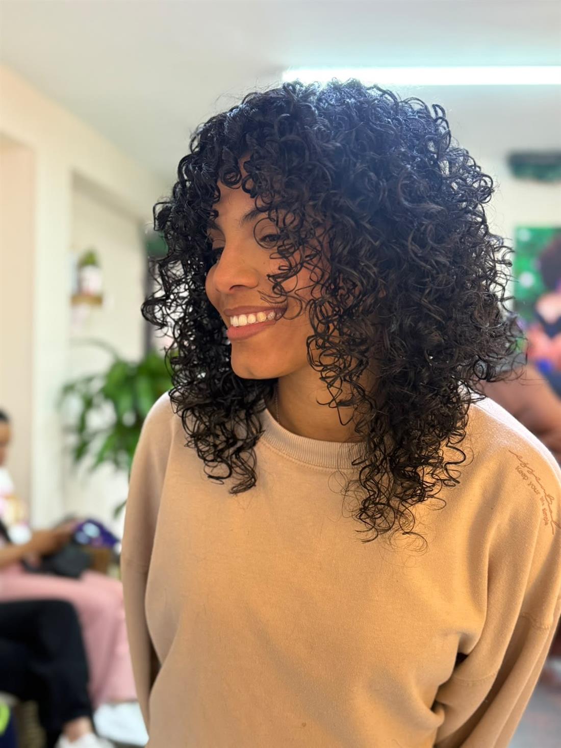 Clienta sonriendo con sus rizos definidos en el salón